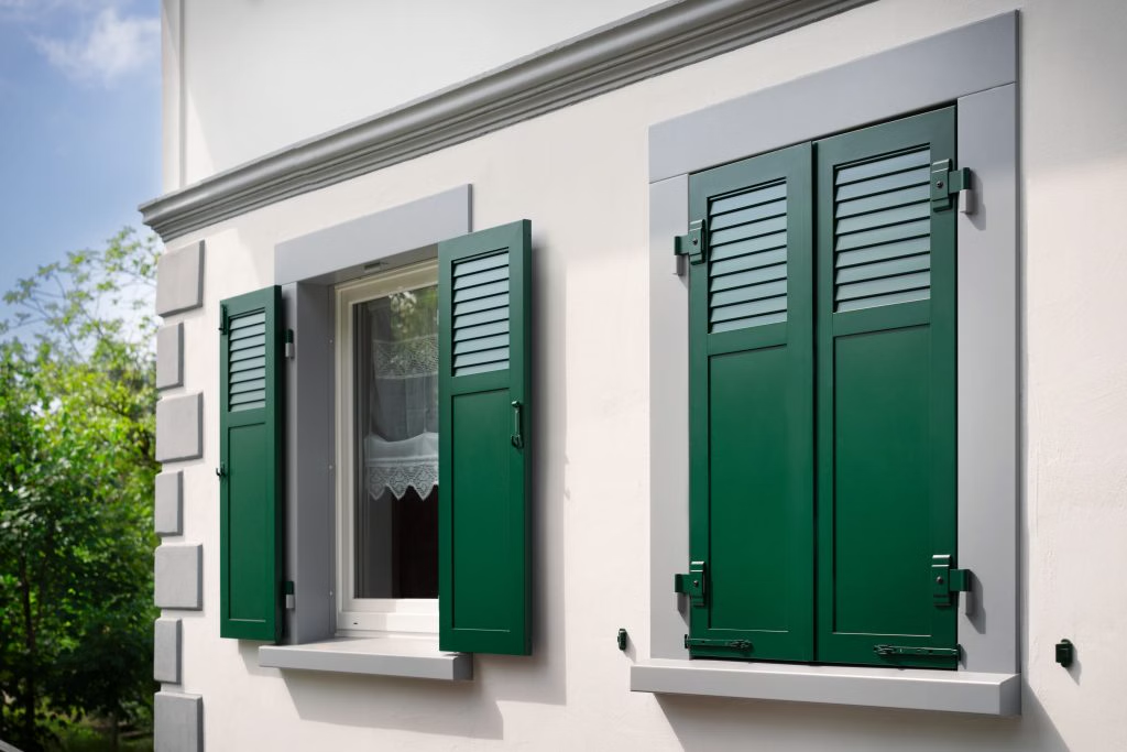 Volets battants aluminium ouverts encadrant une fenêtre de maison individuelle