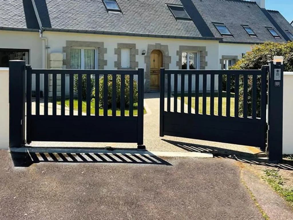 Portail battant aluminium noir à barreaudage vertical, motorisé, devant une maison en pierre du Val d’Oise