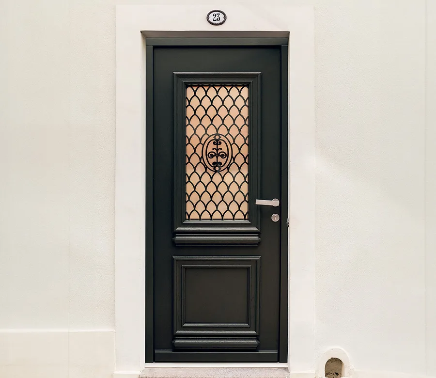 Porte d’entrée bois peinte en noir avec grille décorative et vitrage, sur un mur clair