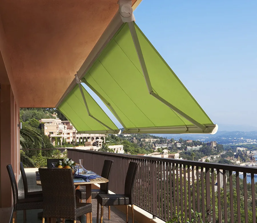 Store banne vert déployé au-dessus d’une terrasse avec table et chaises