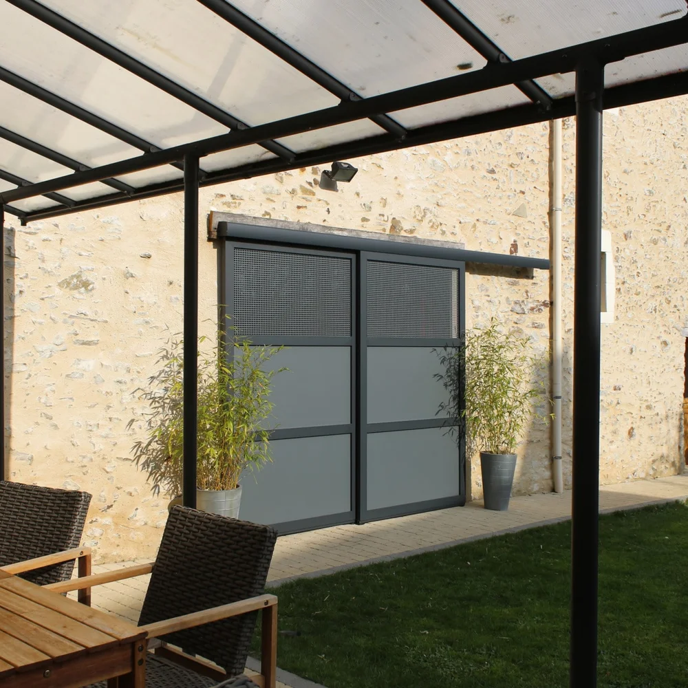 Volets battants aluminium gris anthracite ouverts sur une façade en pierre