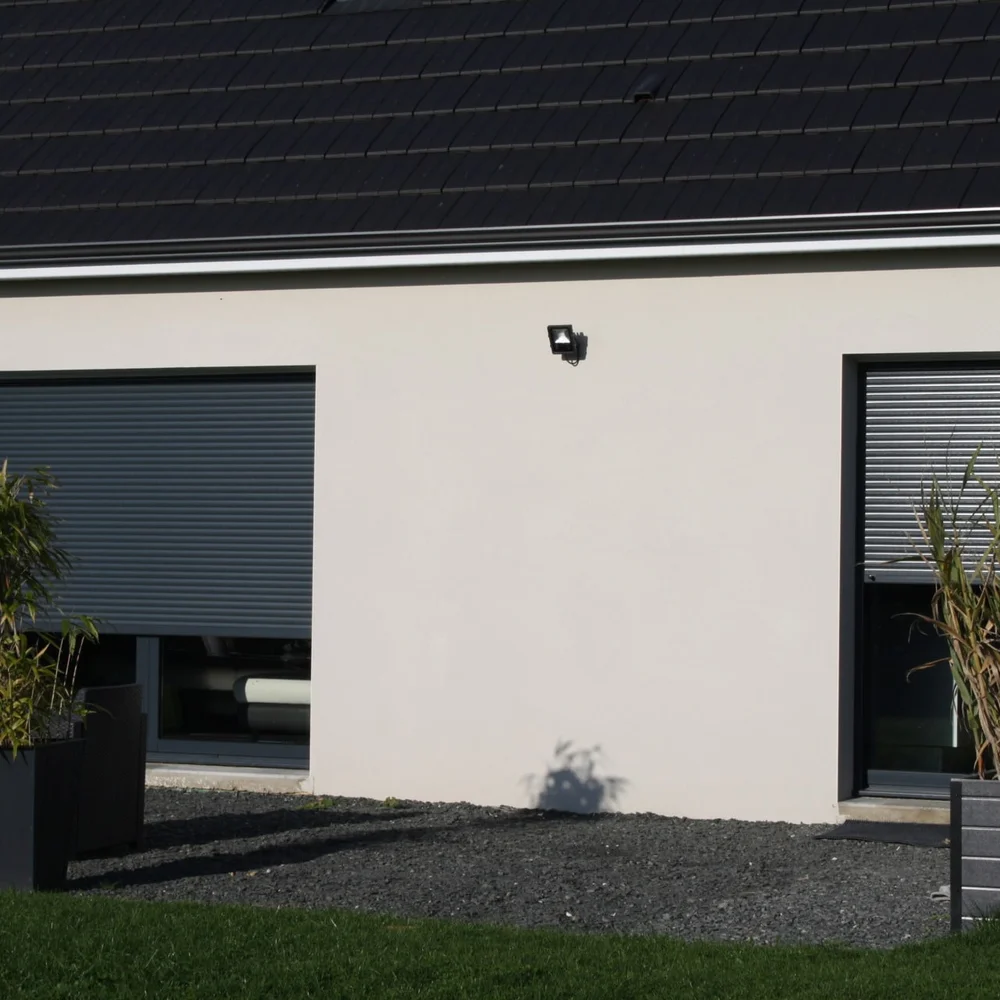Volet roulant aluminium gris anthracite descendu sur une large baie, façade blanche